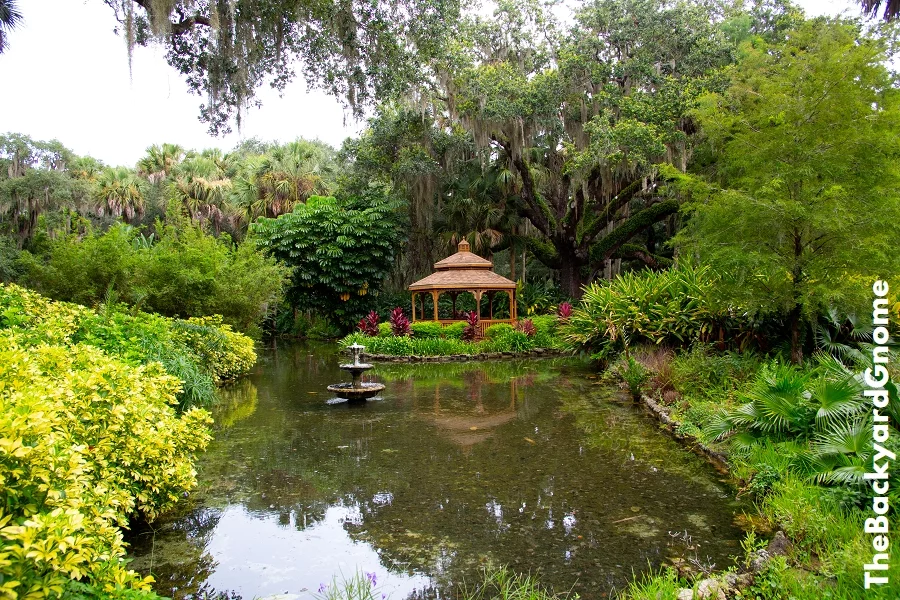 A garden landscape showing a gazebo and a pond