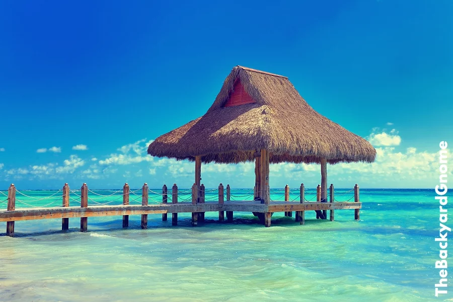 Tropical white sandy beach. Palm leaf roofed wooden pier with gazebo on the beach. Punta Cana, Dominican Republic
